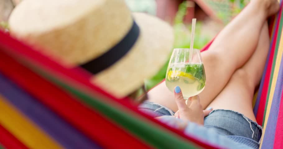 Young woman drinking cocktail while lying in comfortable hammock at green garden Royalty-Free Stock Footage #1105322723
