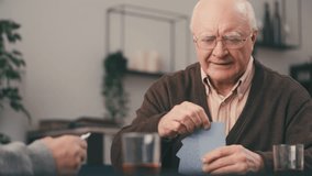 Cheerful senior man playing card game with a friend and smiling, leisure time - Powered by Shutterstock - Get 15% off with code: PIKWIZARD15