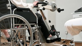 An unrecognizable elderly woman does pedal exercises from wheel chair at hospital. High quality photo.