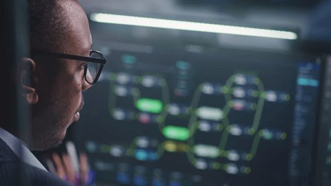 African American software engineer looks at computer screen with displayed big data server and blockchain network, monitors real-time analysis charts in monitoring office. Concept of cyber security. - Βίντεο στοκ