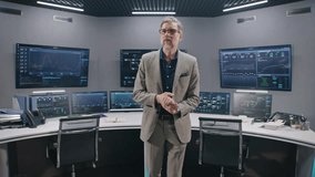 Mature supervisor greets IT programmers in monitoring room. Big data engineers sit at computers with professional software. Multiple big screens with displayed real-time analysis charts. Dolly shot. - Powered by Shutterstock - Get 15% off with code: PIKWIZARD15