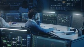 Software engineer works at computer in monitoring room late night. Big data scientists analyze server data. Multiple big screens on the wall with displayed real-time analysis charts. Cyber security. - Powered by Shutterstock - Get 15% off with code: PIKWIZARD15