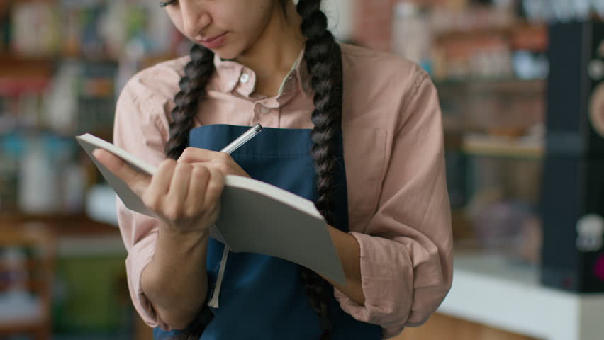 Indian arabian female staff waitress writing in notebook taking customer order in cafe woman catering employee worker take reservation serving restaurant client in cafeteria catering service concept Royalty-Free Stock Footage #1105335405