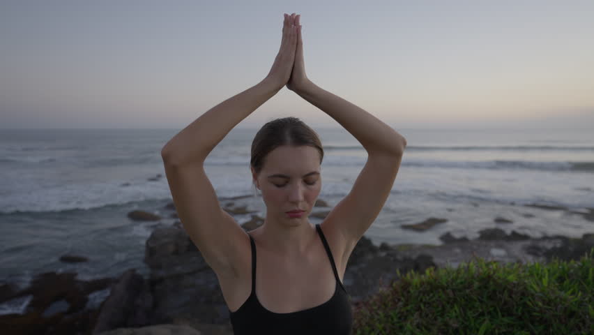 Close up Yoga exercises and meditation with ocean view on sunset. Caucasian fit woman doing yoga training on seashore. Healthy lifestyle concept.