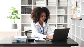 
Confident business expert attractive smiling young African woman holding digital tablet  on desk in creative office.