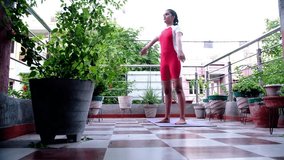 front view of a young girl practicing rainbow yoga on her terrace garden shows that she is able to bear the weight of her entire body on her arms