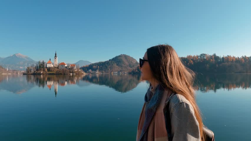 Tourist travel Europe. Close up woman admire Bled Castle and Church on the Island on the Lake Bled, Slovenia. Autumn time in Europe Royalty-Free Stock Footage #1105351955