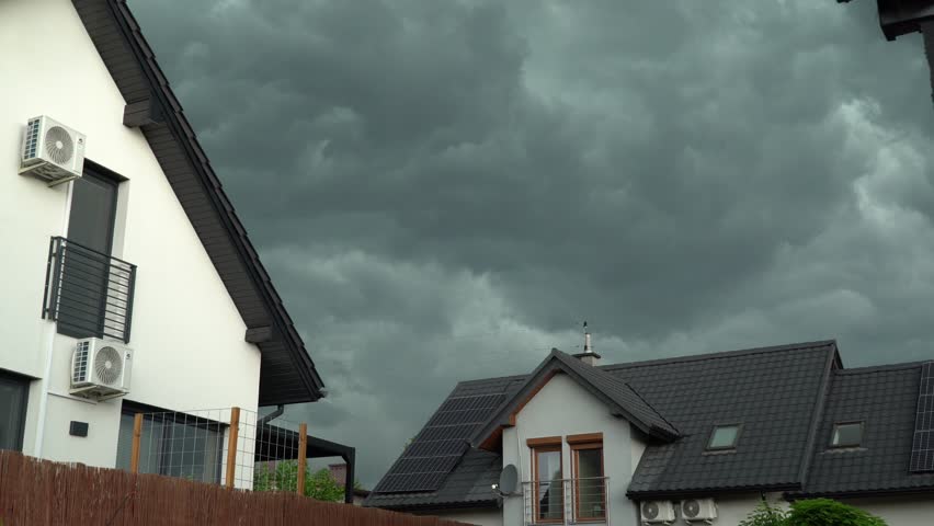 Dark storm clouds are approaching. Nearby houses visible.