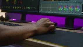 Close up shot of hand of video maker editing movie, making color correction, using computer mouse. Program interface with color tools, RGB wheels and levels on PC screen. Film post production concept.