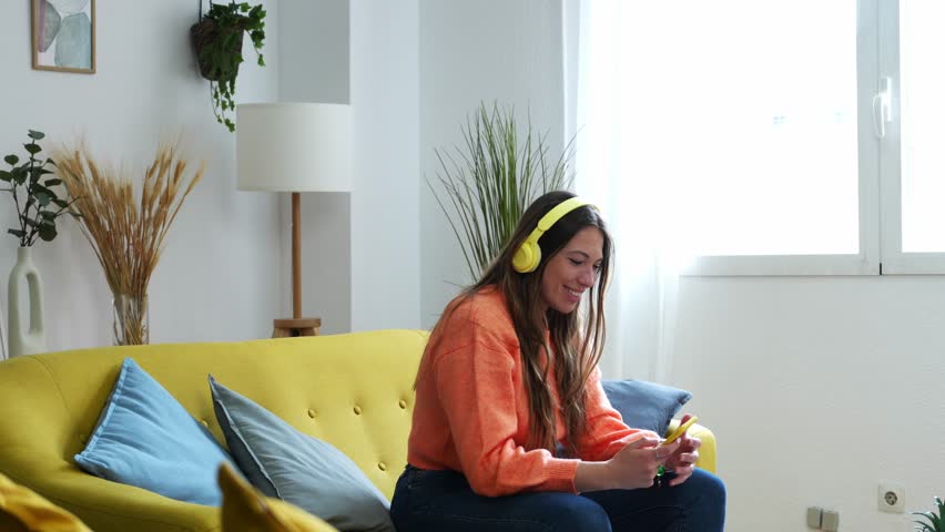 Woman sitting in living room dancing while listening to music.