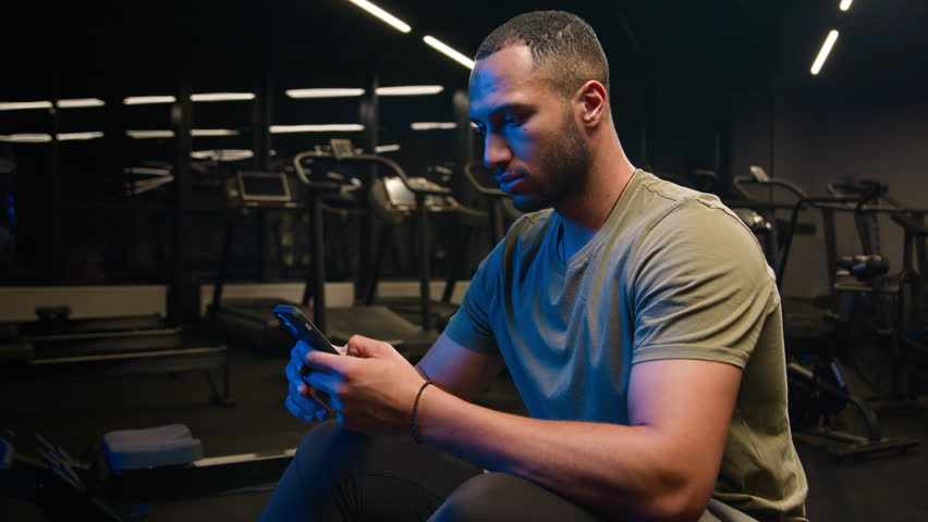 African American fitness man athlete personal trainer using smartphone sportsman browsing online messages mobile phone sharing workout photos on social media chatting online sport app service in gym Royalty-Free Stock Footage #1105372875