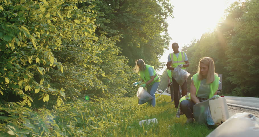 Multi-ethnic group of conservation volunteers cleaning up roadside on sunny day. Team of young people picking up rubbish. Ecology and social responsibility in urban environment. Royalty-Free Stock Footage #1105374253