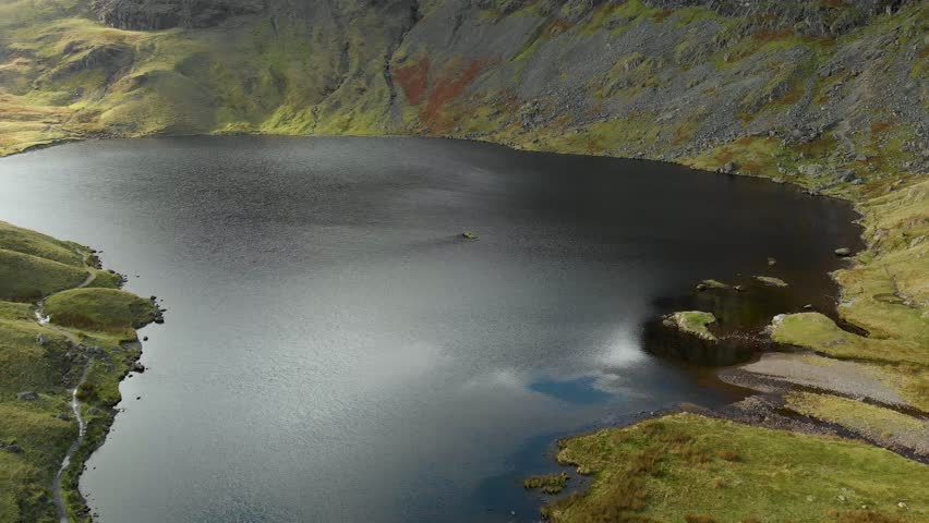Aerial view of Stickle Tarn lake, located in the Lake District, Cumbria, UK. Popular tourist attractions in Great Langdale valley, famous for its glacial ribbon lakes and rugged mountains.