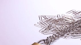 Paper clips, chain and lock on white background rotating 