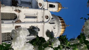 View of Cathedral of Christ the Saviour in Moscow, Russia through frame of white blooming flowers. Clear blue sky. Slow motion vertical video. Easter holiday theme.	