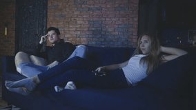 Guy and girl bored switch channels on TV in living room. Couple connecting and spend time in evening or night together. Young family watching television at home. Concept of leisure or entertainment. - Powered by Shutterstock - Get 15% off with code: PIKWIZARD15