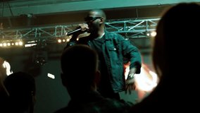 African-American Black rap artist performing his gig in front of a concert crowd on a stage of a large venue, surrounded by bright flashig lights - Powered by Shutterstock - Get 15% off with code: PIKWIZARD15