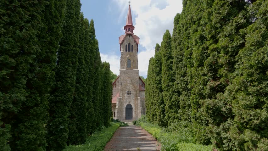 Stone neo-gothic catholic church of St. Anthony of Padua of the end of the 19th century in Losyach village, Ukraine. View while moving forward along the alley of juniper trees
 Royalty-Free Stock Footage #1105394855