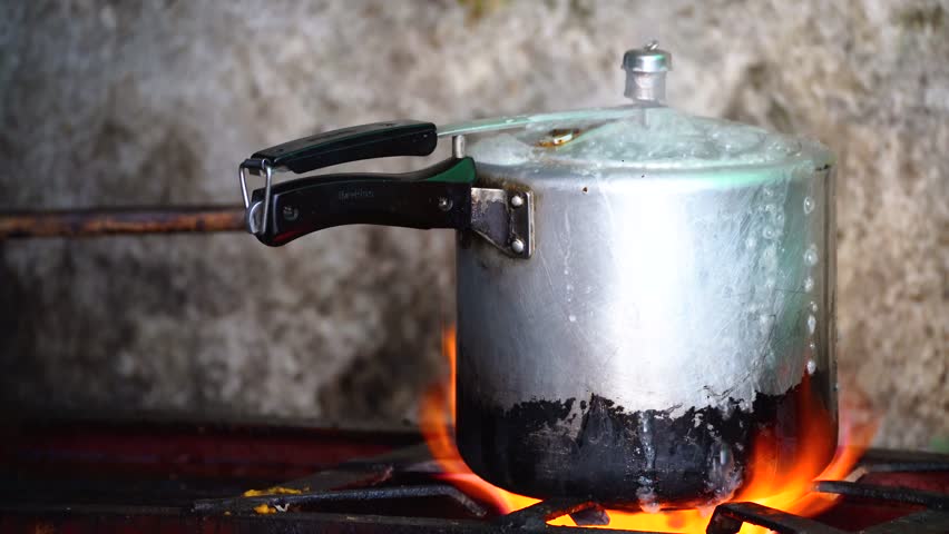 old pressure cooker on a gas flame whistling as it gives off steam the perfect utensil to make stews, meats and vegetables with rice Royalty-Free Stock Footage #1105396431