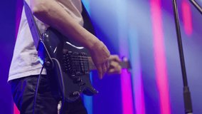  Close-up hands of musician playing an electric guitar on stage. Male musician with an electric guitar in his hands