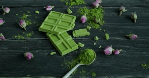 Woman grabbing a pieces of Matcha chocolate from table, green chocolate bar placed on table, healthy vegan snack, slow motion video, close-up 4k footage
