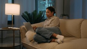 African American woman girl relax on comfortable couch shopping online night time social media addict smiling ethnic female freelancer studying working from home order delivery use laptop application - Powered by Shutterstock - Get 15% off with code: PIKWIZARD15