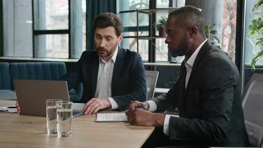 Caucasian manager showing African boss bad business result computer mistake two diverse men multiracial coworkers businessmen with papers and laptop sad upset failure discuss startup problem at office Royalty-Free Stock Footage #1105402097