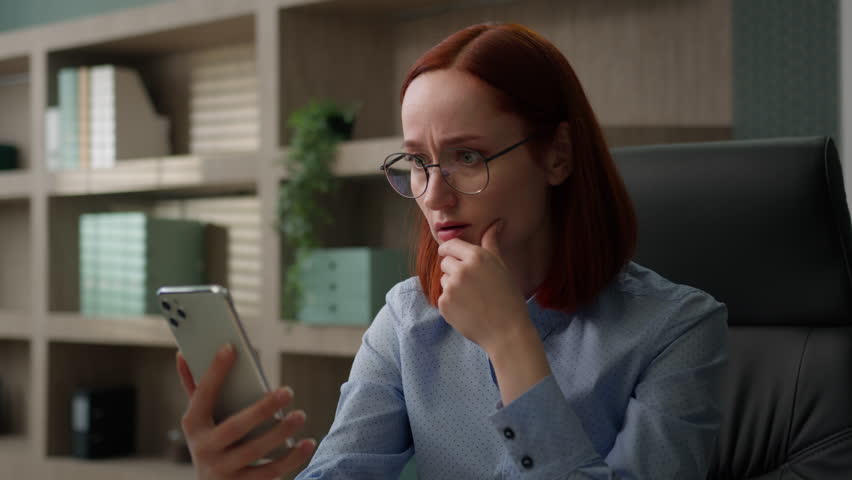 Caucasian shock stressed sad woman at desk in office with smartphone unhappy negative emotions upset business girl businesswoman take off glasses stress bad news terrible SMS mobile phone failure lost Royalty-Free Stock Footage #1105402105