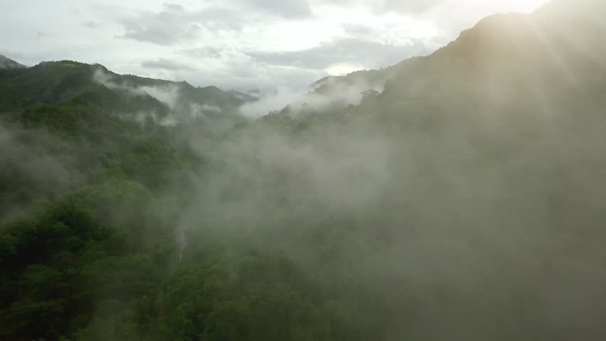 Aerial view flying above lush green tropical rain forest mountain with rain cloud cover during the rainy season on the Doi Phuka Mountain reserved national park the northern Thailand