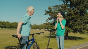 Joyful attractive mature woman in cycling helmet wit electric scooter and positive handsome senior man with bicycle enjoying active lifestyle on retirement , discussing travel route in public park. - Powered by Shutterstock - Get 15% off with code: PIKWIZARD15