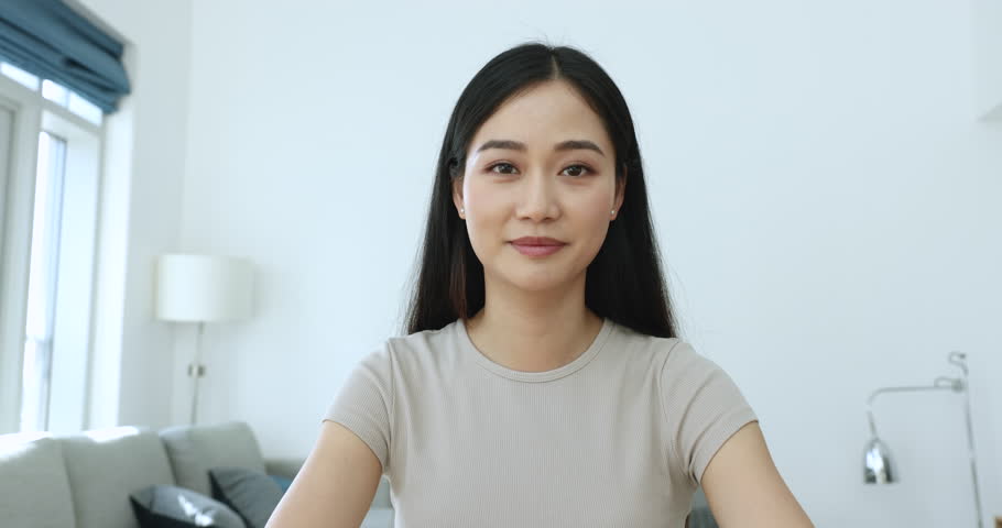 Pretty Asian woman talk to camera seated in living room, give consultation to client remotely, pass job interview, record video for vlog, share news to family, experience with subscribers, webcam view Royalty-Free Stock Footage #1105408727