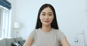 Pretty Asian woman talk to camera seated in living room, give consultation to client remotely, pass job interview, record video for vlog, share news to family, experience with subscribers, webcam view