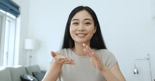 Pretty Asian woman talk to camera seated in living room, give consultation to client remotely, pass job interview, record video for vlog, share news to family, experience with subscribers, webcam view