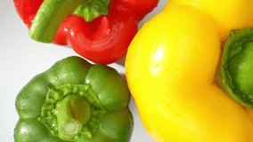 The macro video featuring succulent green, fiery red, and sunny yellow bell peppers. The intricate details of their textured skins come alive as each pepper is adorned with delicate droplets of water
