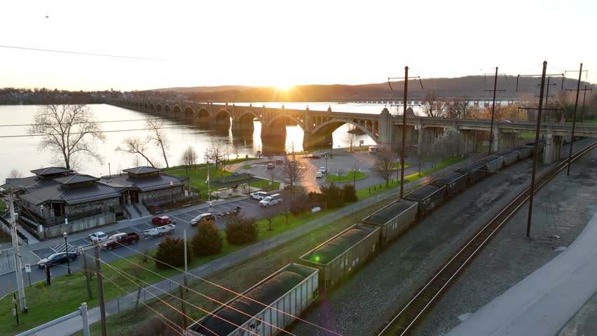 Downtown riverfront in Columbia, Pennsylvania at sunset, with an Amtrak depot, spectacular bridge crossing the river and freight trains passing by.