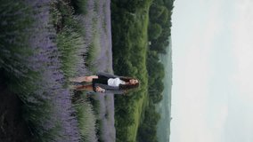 
Romantic beautiful woman walking along a path in a lavender field. A beautiful woman touches flowers and enjoys life, an endless blooming field. Beautiful rural landscape. 4k, ProRes. Vertical video
