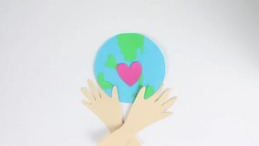 Green globe planet eco concept. Earth day postcard close up. Stop motion paper animation. Pink heart beating. Ecology concept. Hands hold love sign. People show hug gesture. Whole world art card. - Powered by Shutterstock - Get 15% off with code: PIKWIZARD15