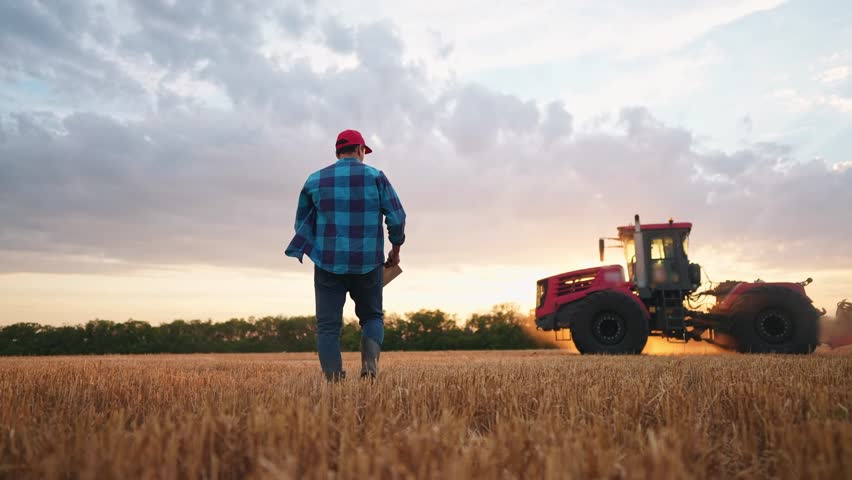 agriculture. farmer walk works in field next to a tractor that plows the land. business agriculture concept. farmer with tablet works in a field next to a tractor at sunset mowed wheat plows farm Royalty-Free Stock Footage #1105416173