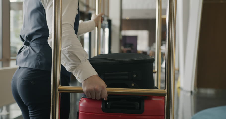 Follow shot of bellman pushing baggage cart along hotel corridor helping customers with luggage working alone. People and job concept. Royalty-Free Stock Footage #1105423047