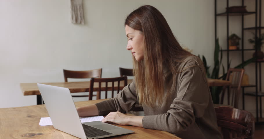 Serious young businesswoman lawyer employee do work using laptop, check agreement details, writing terms, reviewing conditions looks focused engaged in workflow seated at office workplace. Paperwork Royalty-Free Stock Footage #1105424355