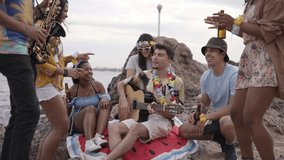Cheerful young people celebrating summer beer party on beach. Multi-ethnic group of happy friends gathered together dancing excited to live music outdoor. Social relations in generation z.  - Powered by Shutterstock - Get 15% off with code: PIKWIZARD15