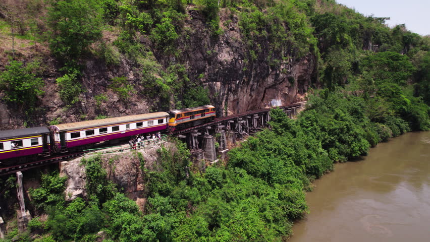 Aerial drone Thailand-Burma Railway Train Maeklong Death Railway bridge over the River Kwai JEATH on mountain pass Royalty-Free Stock Footage #1105428971