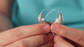 Hearing aids in hands making heart shape over blue background. Closeup of listening device for people with hearing disorder, disfunction. Technology that gives better sense of sound, speach - Powered by Shutterstock - Get 15% off with code: PIKWIZARD15