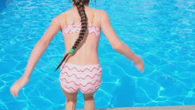 Happy fun loving girl jumping and diving into the swimming pool at a pool party on a summer sunny day. Slow motion full HD resolution swimming pool video
