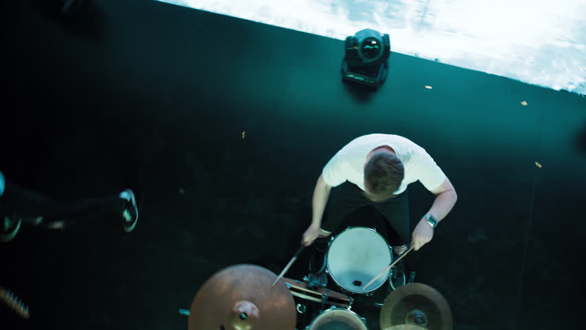 Jib shot of a drummer performing his solo during rock band concert on stage of a large venue, surrounded by bright flashing stage lights Royalty-Free Stock Footage #1105443807