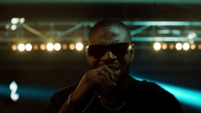 African-American Black rap artist performing his gig on a stage of a large venue, surrounded by bright flashig lights - Powered by Shutterstock - Get 15% off with code: PIKWIZARD15