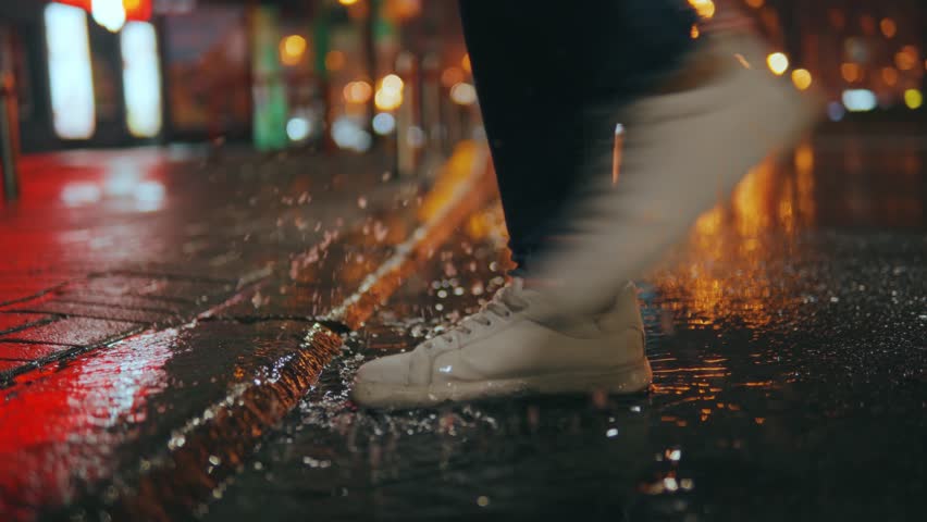 Close-up of a woman's feet stepping into a muddy puddle and making a splash