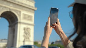 Happy young girl tourist taking photo on smartphone of Arc de Triomphe