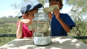 In this captivating video, two children, aged 5 and 8, are seen diligently saving money in a glass jar. They carefully place both dollars and bitcoins into the jar, showcasing their financial awarenes
