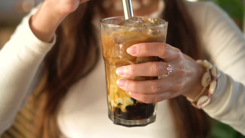 a woman mixing and drinking ice bubble coffee tea  Royalty-Free Stock Footage #1105459889